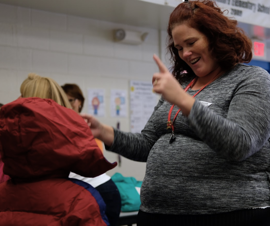 Smiling teacher providing a student in need with a free operation warm winter coat.